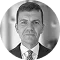 Headshot of a man in a suit, looking directly at the camera with a neutral expression.