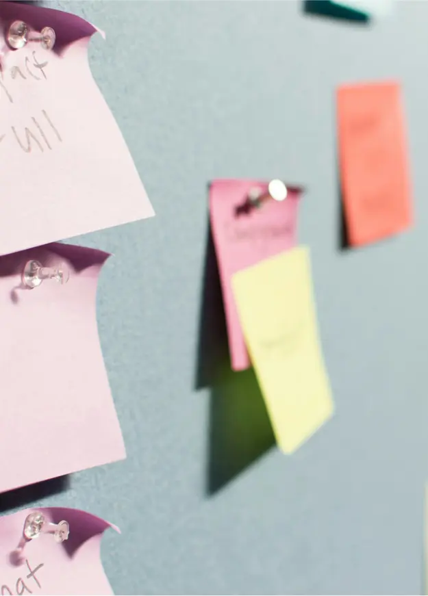 Colorful sticky notes pinned to a blue wall, with some handwritten text visible.