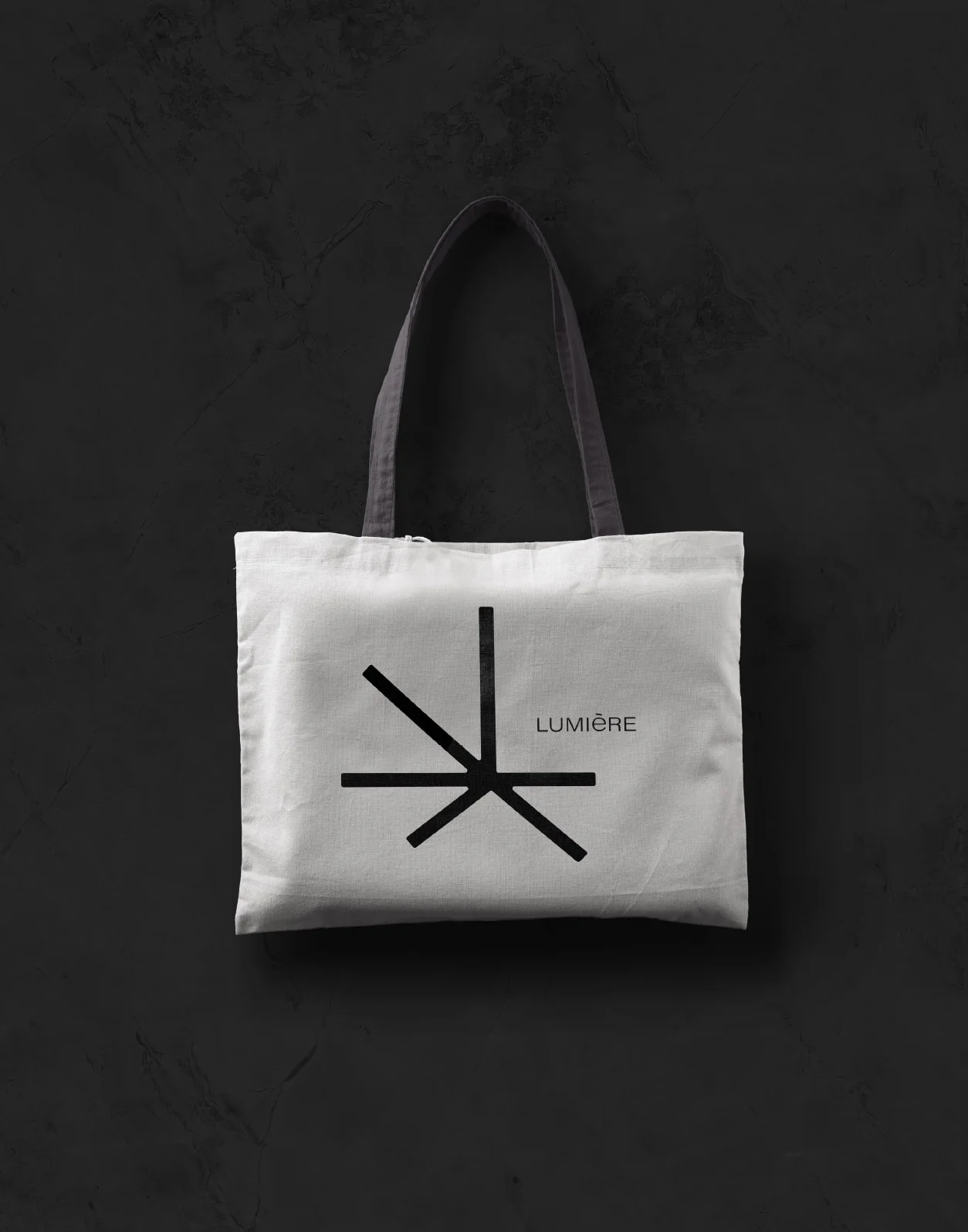 White tote bag featuring a minimalist black logo design with the word "LUMIÈRE.