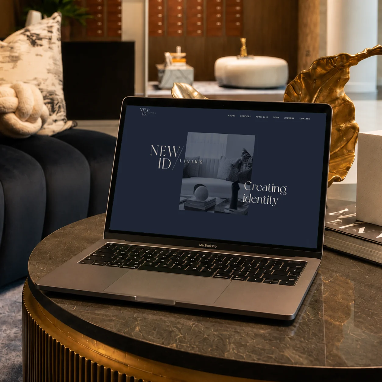 Laptop on a coffee table displaying a website titled "NEW ID" with a dark background and modern design elements.